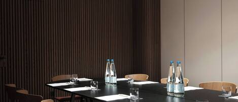 A conference room with a long table, chairs, water bottles, and glasses.