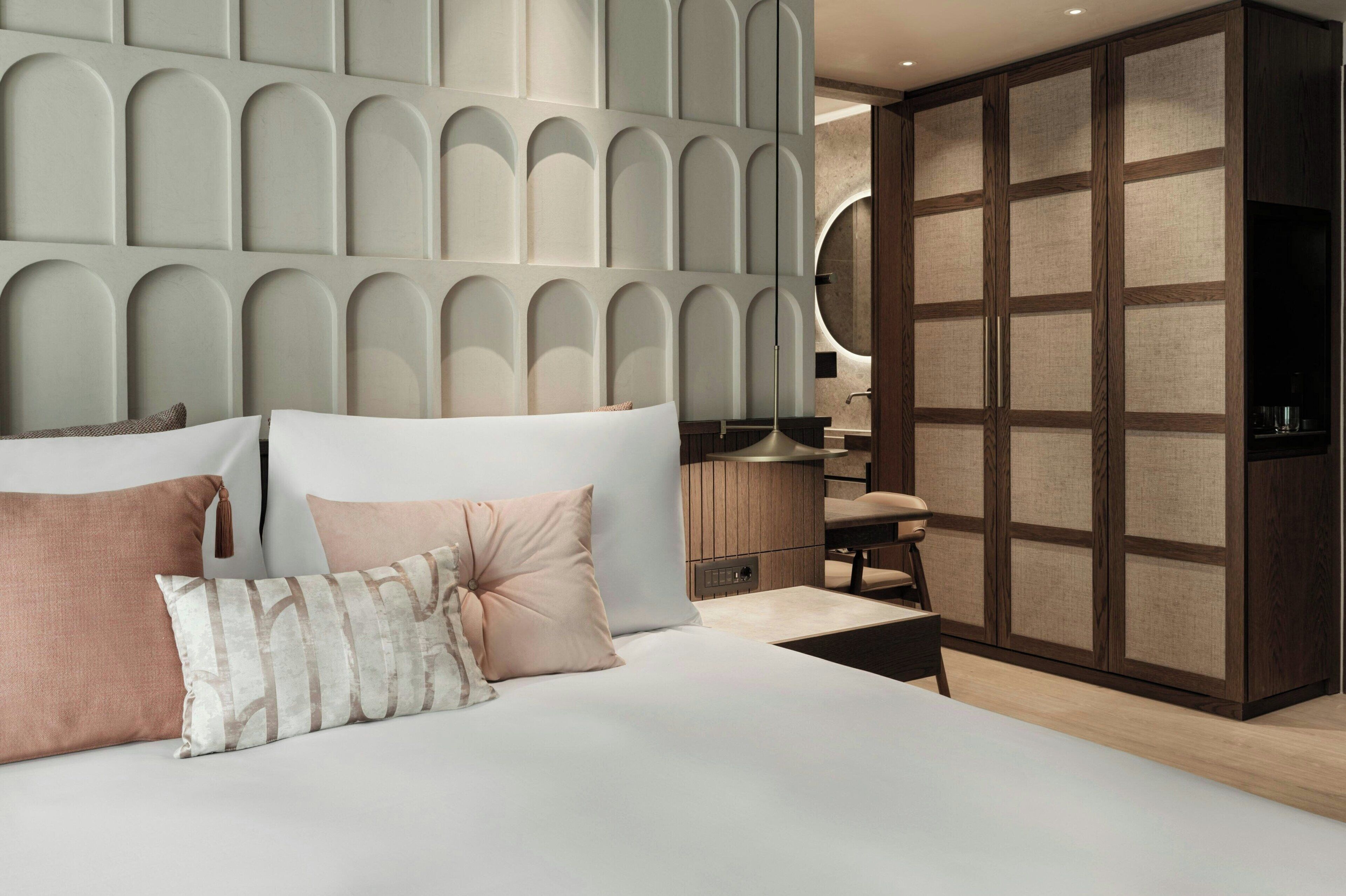 Un dormitorio moderno con una cama grande, un armario de madera y una mesita de noche.