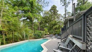 A swimming pool with a wooden deck, surrounded by lush greenery and trees. - 6 Painted Bunting at The Sea Pines Resort (Hilton Head Island)
