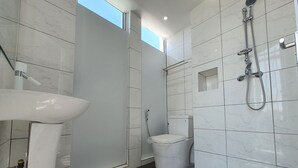 Een moderne badkamer met een wit wastafel, toilet en douche.