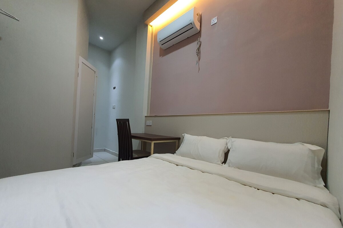Een hotelkamer met een bed, een bureau en een airconditioner aan de muur.