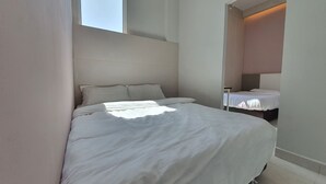 Een slaapkamer met een groot bed, een nachtkastje en een raam.