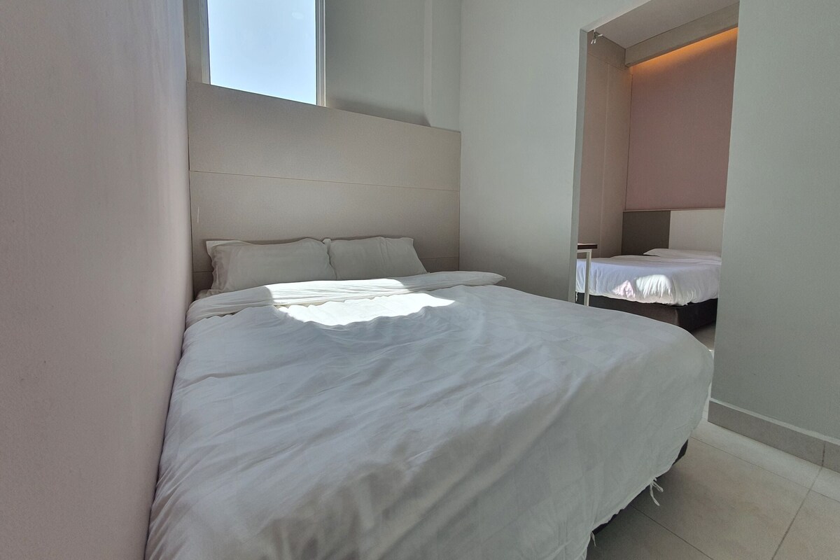Een slaapkamer met een groot bed, een nachtkastje en een raam.