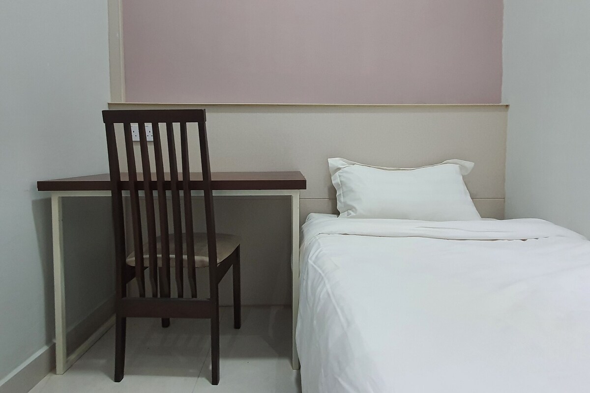 Een kleine kamer met een bed, een bureau en een stoel.