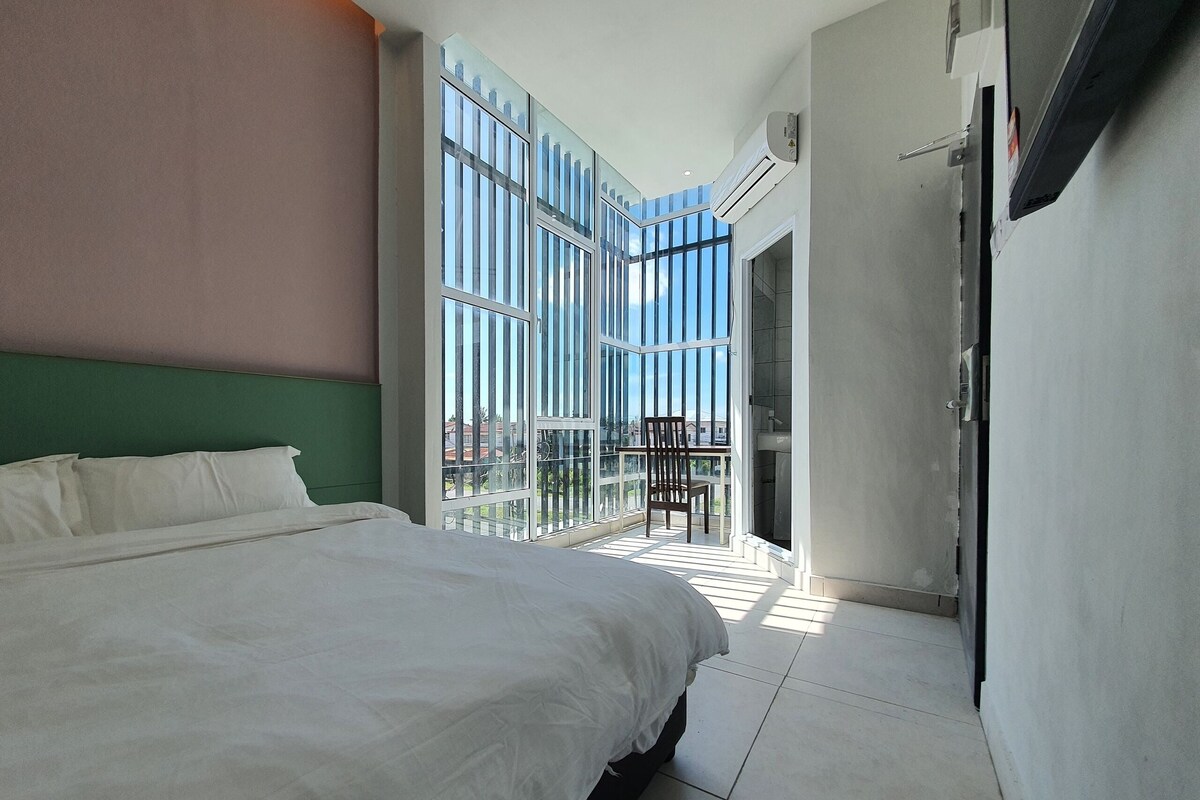 Een moderne hotelkamer met een groot bed, een balkon met een stoel en uitzicht op de stad.