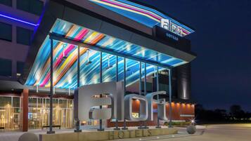 A hotel with a modern facade, large glass windows, and a colorful ceiling design.
