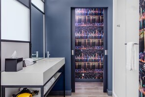 A modern bathroom with a large mirror, a white sink, and a towel rack. - Aloft by Marriott Dallas Arlington South (Arlington)
