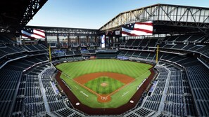 A baseball stadium with multiple seating tiers, a central field, and large flags. - Aloft by Marriott Dallas Arlington South (Arlington)