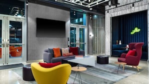 Un espace de détente moderne comprenant un canapé, des fauteuils, une table basse et une scène agrémentée d’un panneau lumineux au néon.