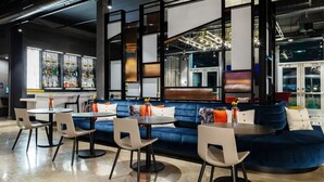Un espace détente moderne avec un canapé bleu, des tables rondes et des chaises.
