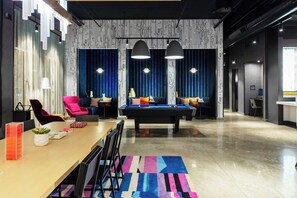 Un área de descanso moderna con mesa de billar, asientos y bar.