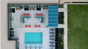 Un espace piscine aménagé sur le toit, comprenant une grande piscine, des chaises longues et un coin salon avec des tables et des chaises.