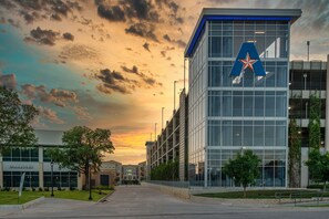 A modern building with a prominent 'A' logo, surrounded by trees and a clear sky. - Aloft by Marriott Dallas Arlington South (Arlington)