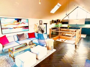 Un salon moderne comprenant un canapé, une table basse et un coin repas séparé par une cloison en verre.