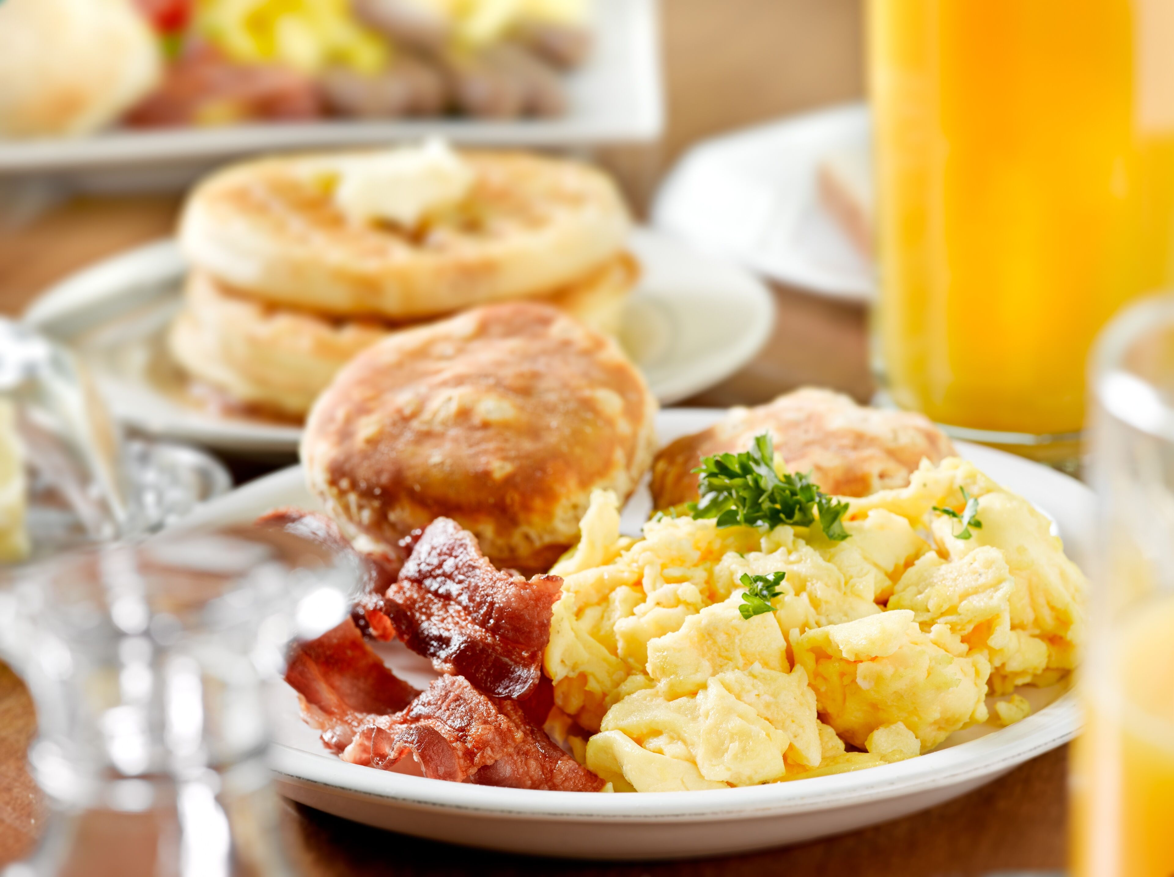 A breakfast plate with scrambled eggs, bacon, and biscuits.