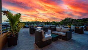 An outdoor seating area with wicker furniture and a view of the sunset.