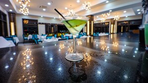 A martini glass with a straw on a wet bar in a well-lit indoor setting.