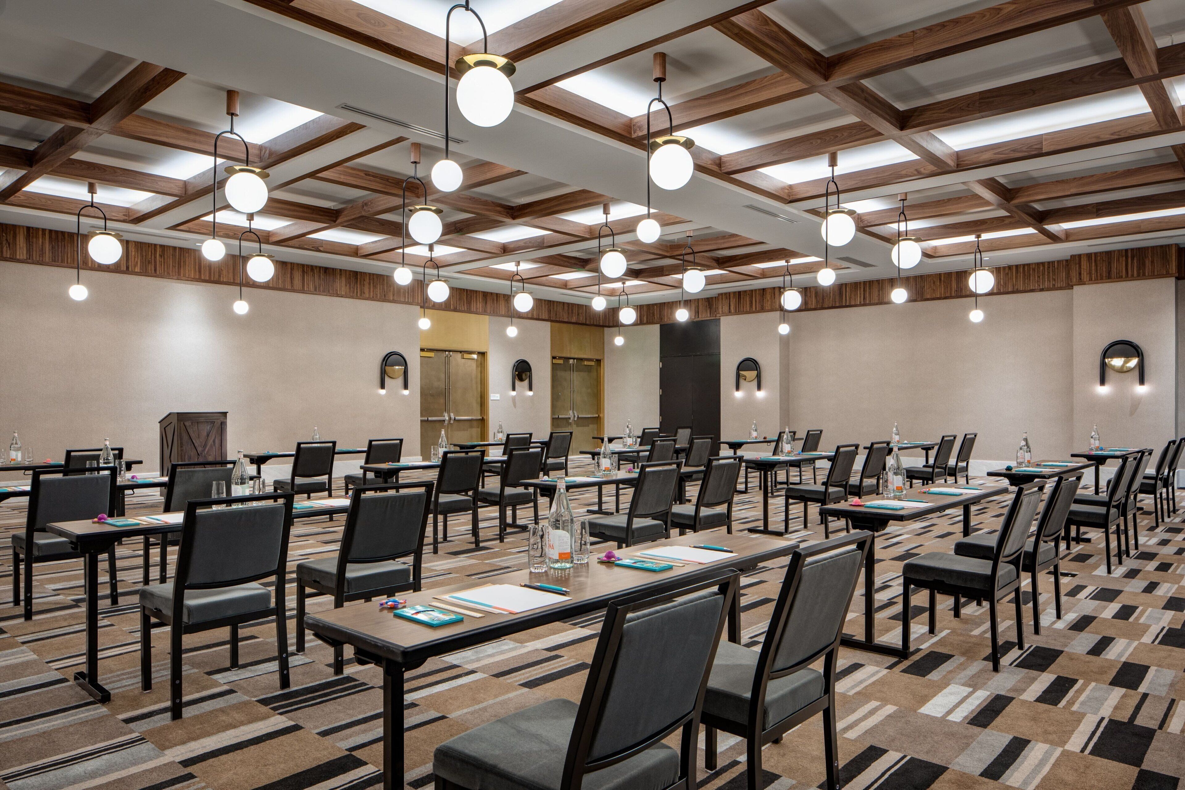 A conference room with multiple tables and chairs, equipped with water bottles and notepads.