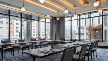 A modern conference room with large windows, multiple tables, and chairs.