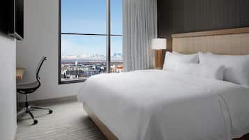 Una habitación de hotel con una cama grande, un escritorio, una silla, un televisor y una ventana con vistas a la ciudad.