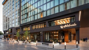 Un hotel moderno con un llamativo letrero que dice 'Adelaide', amplias ventanas y una zona de entrada bien iluminada.