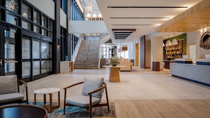 Un vestíbulo amplio con una escalera, zona de estar y mostrador de recepción.