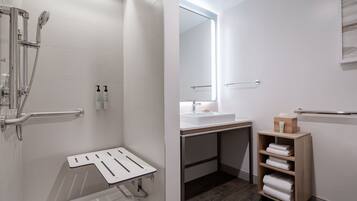 A modern bathroom with a walk-in shower, a bathtub, a sink, and a wooden shelf with towels.