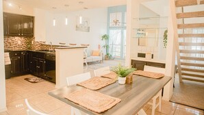 A modern kitchen with dark cabinets, a wooden island, and a dining area with a long table and chairs.