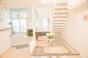Una cocina moderna con una mesa de madera, sillas blancas y una escalera.