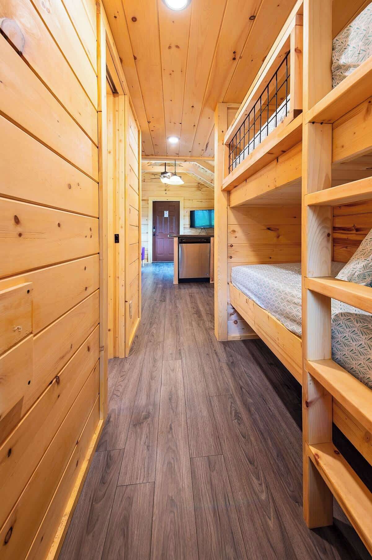 Un interior de madera con literas, una zona de cocina y un pasillo.