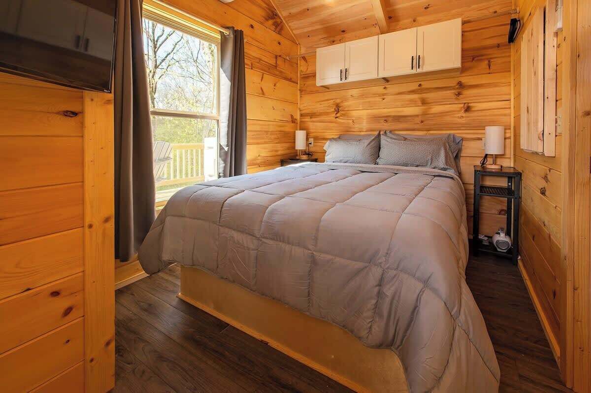 A wooden cabin bedroom with a bed, nightstands, and a window.