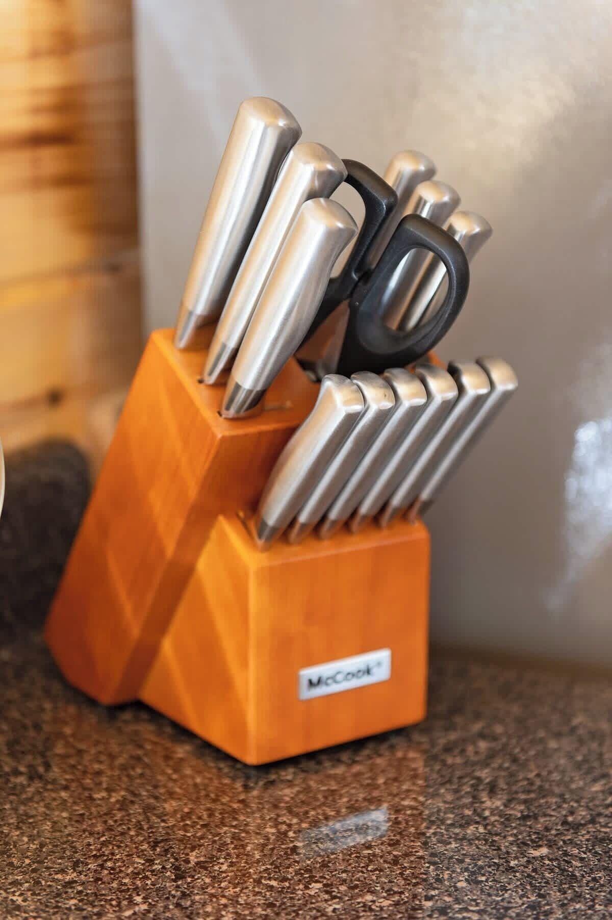 A kitchen utensil holder with multiple knives and a black handle.