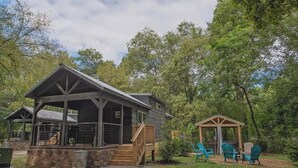 En hytte med en overdækket veranda, udendørs siddepladser og en pavillon.