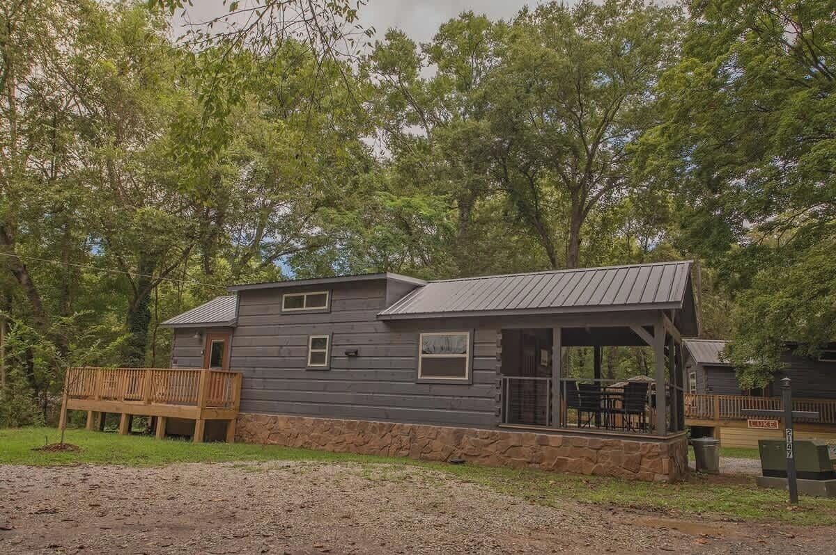 Een chalet met een veranda, een stenen fundering en een metalen dak.