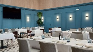 A spacious dining area with multiple tables and chairs, a patterned floor, and a ceiling with hanging lights. - Hotel Don Pepo (Lobón)
