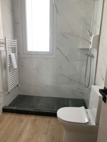 Un baño moderno con ducha, inodoro y ventana.