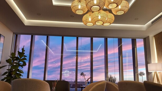 A modern living room with large windows, a sofa, chairs, and a hanging light fixture. - Hotel Don Pepo (Lobón)