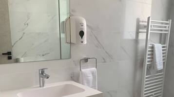 Un baño moderno con salpicadero de mármol, un lavabo blanco, un perchero y un secador de manos.