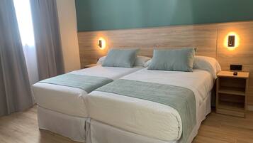 A double bed with two pillows, a bedside table, and a wall-mounted light fixture.