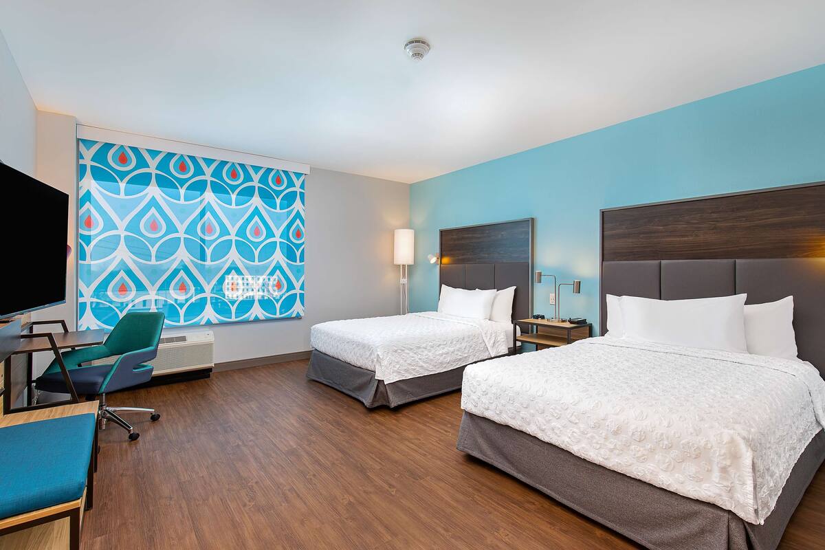 Een hotelkamer met twee bedden, een bureau, een stoel en een televisie.