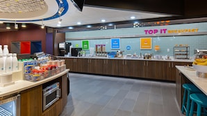En frukosthörna med en disk där olika matvaror visas och en skylt med texten ”TOP IT BREAKFAST”.