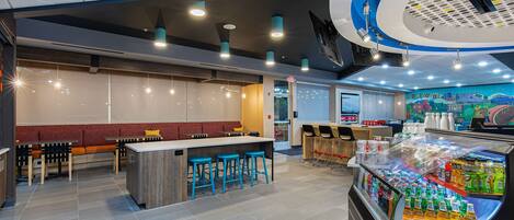 A modern restaurant interior with a bar area, seating, and a beverage display.