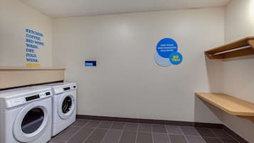 Une buanderie équipée de deux machines à laver à chargement frontal, d’un porte-serviettes et d’un panneau indiquant les instructions de lavage.