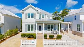 A two-story house with a front porch, a covered entryway, and a small garden area. - Coastal Luxury Cottage | Beach Access | Pet Friendly (Orange Beach)