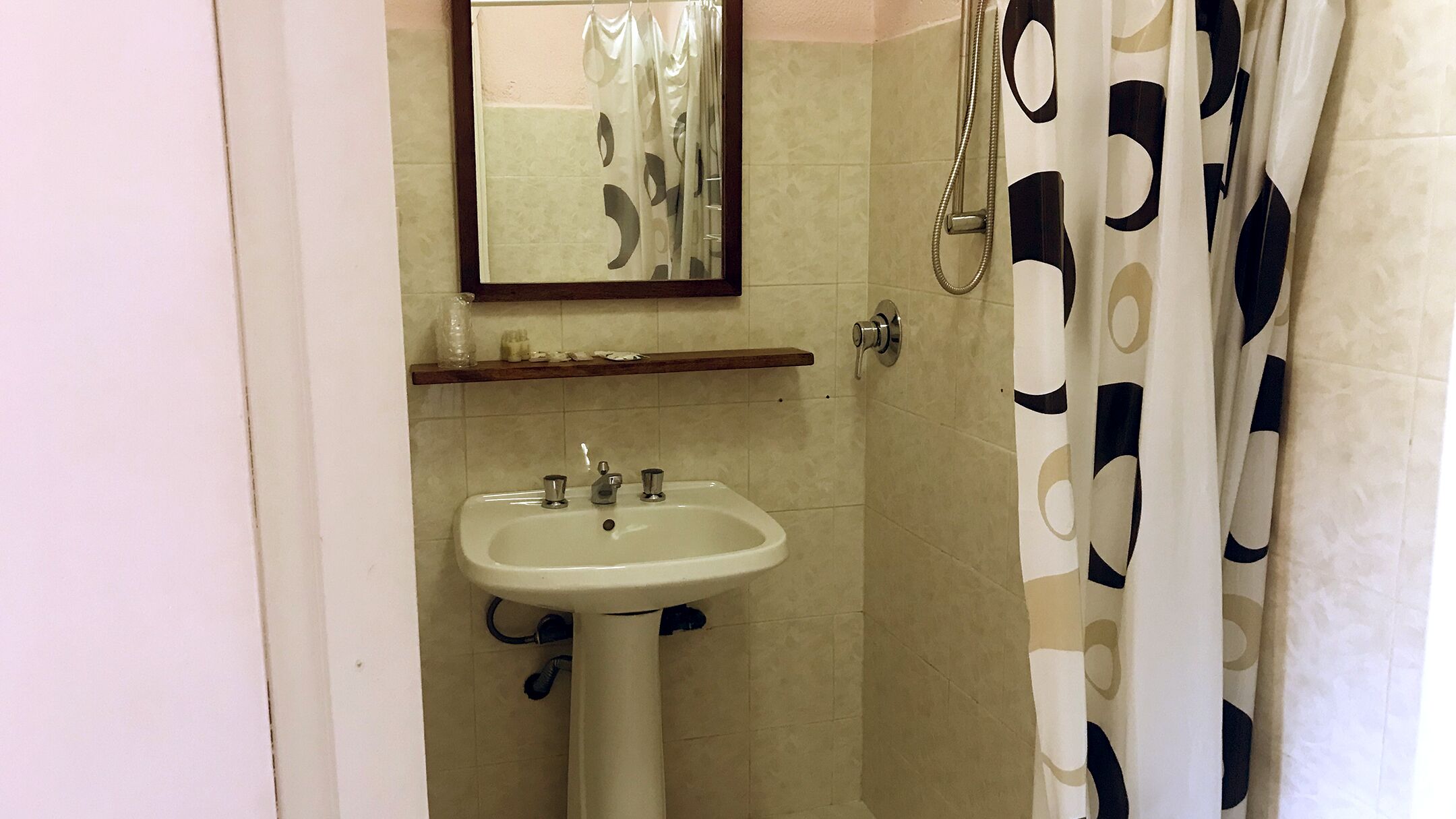 Een badkamer met een wastafel, spiegel, douche en handdoekrek.