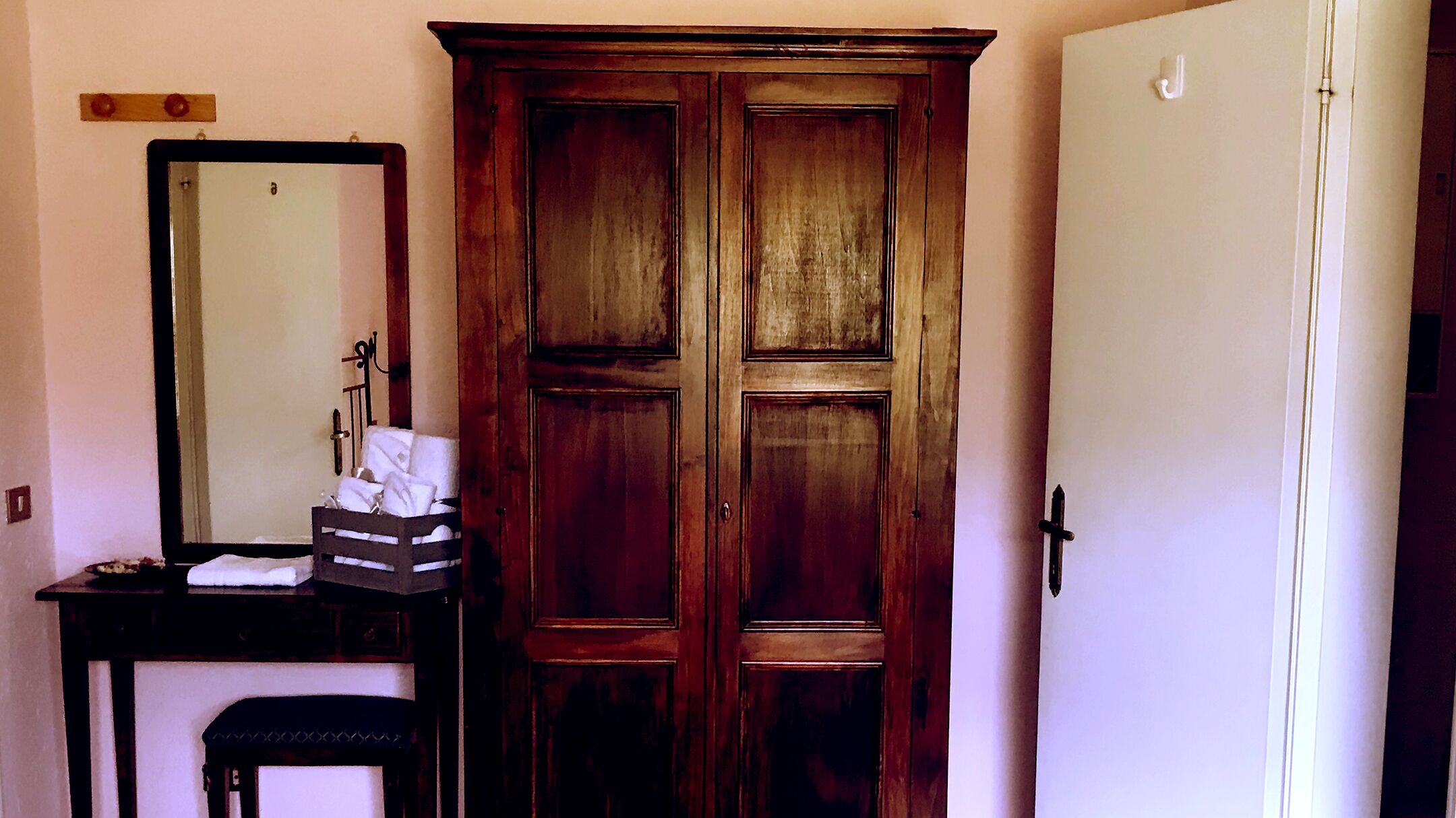 Une pièce avec une armoire en bois, un miroir et un petit banc.