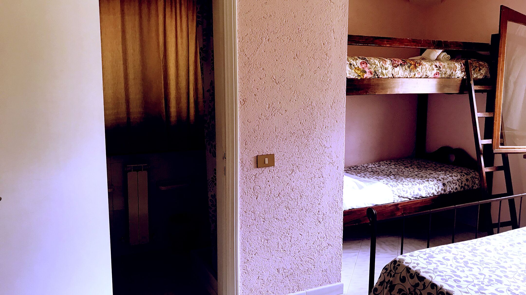 Una camera del dormitorio con letti a castello, una scala, una porta e un interruttore a parete.
