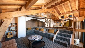 Una habitación estilo loft acogedora, con techo alto, vigas de madera, un rincón de estar integrado y una pequeña mesa redonda, además de una guitarra.