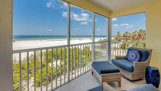 A balcony with a view of the beach, wicker furniture, and a railing. - Vacation Villas #233 Luxury Beachfront Condo (Fort Myers Beach)