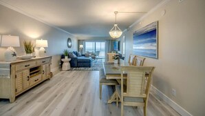 A spacious living area with a dining table, a sofa, and a chandelier. - Vacation Villas #233 Luxury Beachfront Condo (Fort Myers Beach)